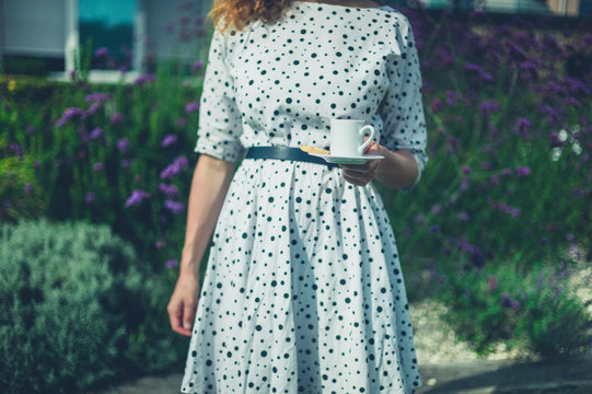 Young woman with cup of coffee in garden