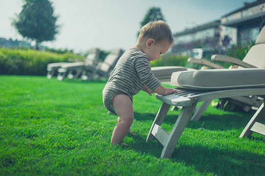 Little baby using deck chair to stand up