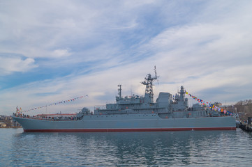 Fototapeta premium Big military battleship moored to the shore in the town bay