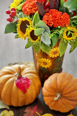 Obraz premium Autumn still life. Autumn bouquet with pumpkins ,sunflowers and leaves on a wooden background. 