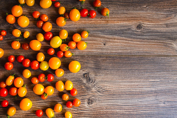 A lot of red and yellow mini tomatoes on the table. Background.