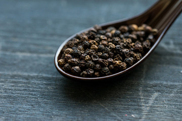 Fototapeta na wymiar Close up black peppercorn in spoon dark background