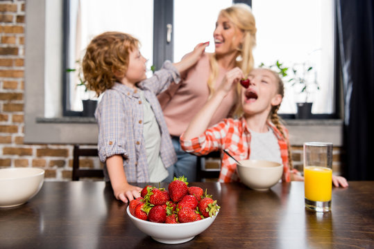 mother with kids eating strawberries