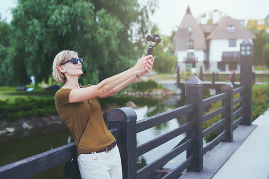 Woman capturing herself with small personal camera in a park