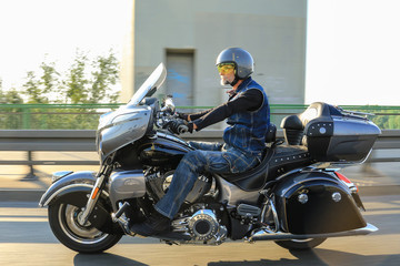 One male motorcyclist riding black motorcycle on the bridge