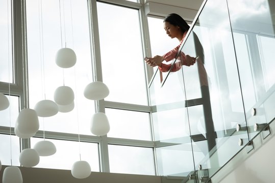 Woman leaning over balcony while using mobile phone