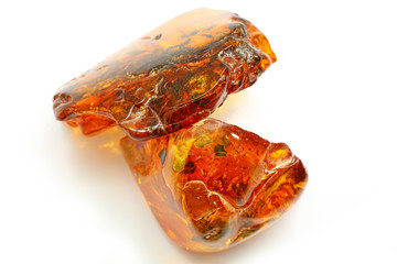 Natural amber. Two extraordinarily beautiful pieces of transparent red amber with inclusions on a white background with a bokeh effect. A natural mineral for juvenile ornaments. Texture of amber