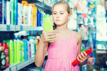 Young girl teenager holding shampoo and conditioner