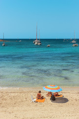 Couple sunbathing on a sand beach with crystal clear waters, Es Carbo in Majorca, Balearic Islands