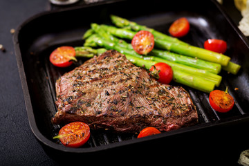 Juicy steak rare beef with spices on a wooden board and garnish of asparagus.