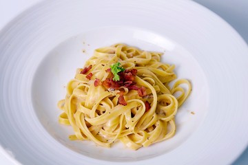 closeup spaghetti carbonara on white plate with bacon 