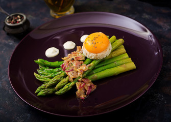 Young shoots of asparagus with ham and chicken egg yolk on toast