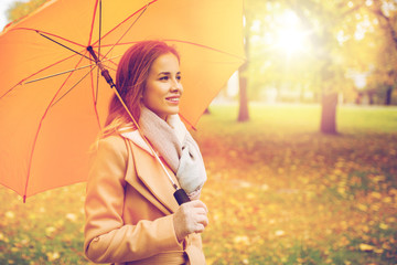 happy woman with umbrella walking in autumn park