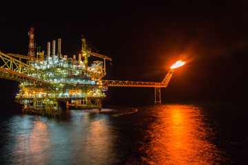Offshore oil and rig platform in sunset or sunrise time. Construction of production process in the sea.