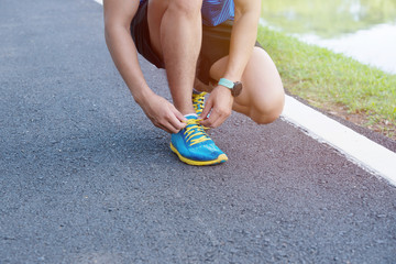 Sport concept, sneakers for running. Man tightening tacings on his sneakers, no face, Legs in professional sport shoes on the track