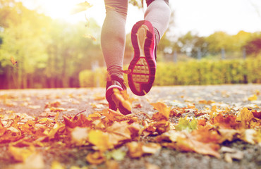 close up of young woman running in autumn park