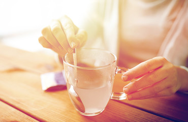 woman stirring medication in cup of water