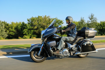 One male motorcyclist riding black motorcycle on the road