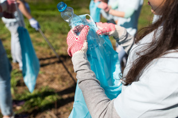 volunteer with trash bag and bottle cleaning area
