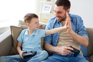 father and son with gamepads doing high five