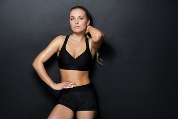 Fototapeta na wymiar young woman in black sportswear posing in gym