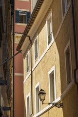 Elegant street lantern of wrought iron and a glass lampshade on the facade of an old building. Rome. Italy