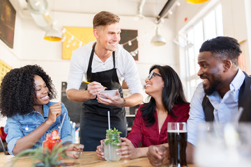 waiter and friends with menu and drinks at bar