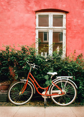 Fototapeta na wymiar The bicycle stands on the street near the olde pink wall