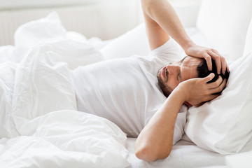man in bed at home suffering from headache