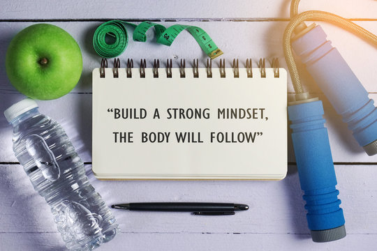 Fitness quotes "Build A Strong Mindset, The Body Will Follow" on open notebook.