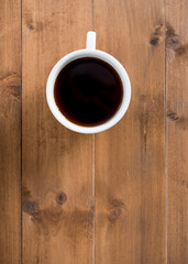 Black coffee in white cup on brown wooden background