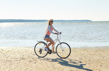 happy woman riding bicycle along summer beach