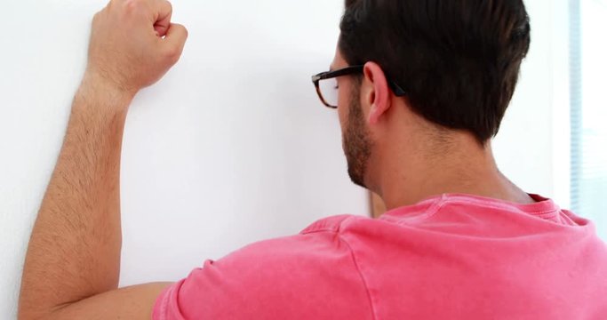 Frustrated executive heating a wall out of rage 