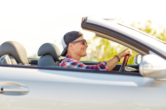 happy young man in shades driving convertible car