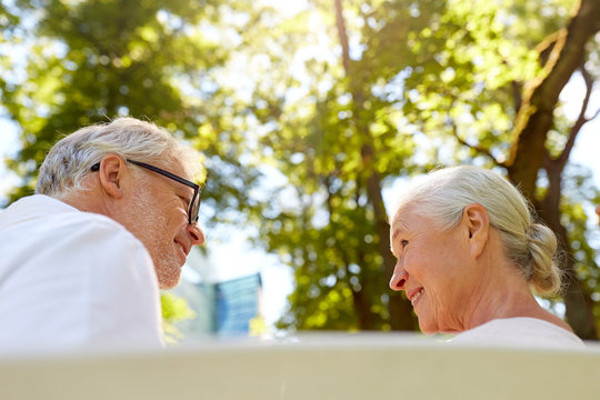 Happy Senior Couple Sitting On Bench At Park