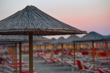 Evening on the beach in Durres: sunset sky, sun beds and many umbrellas. Summer in Albania.