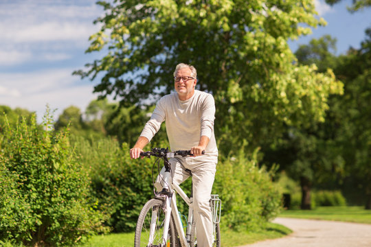 happy senior man riding bicycle at summer park