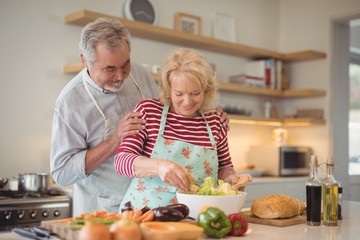 Senior couple mixing vegetables salad in bowl