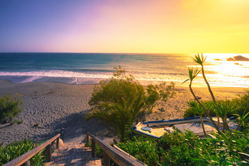 Naklejka premium Tropical sandy beach of Ligres, Crete, Greece, with big waves at colorful sunset.