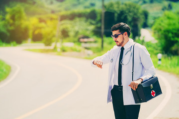 Young doctors check the time waiting for the hospital car to travel to treat the patient. Rural doctor concept. - 169953437