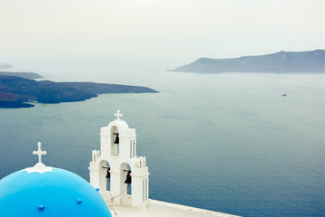 Fototapeta na wymiar Bell tower of an orthodox church at Santorini with volcano at the background, Greece.