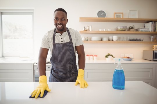 Smiling man cleaning the kitchen worktop
