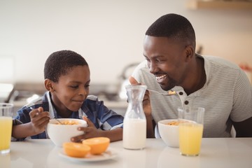Father and son having breakfast in kitchen