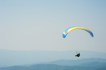 A paraglider fly over a mountain valley on a sunny summer day. Paragliding in the Carpathians in...