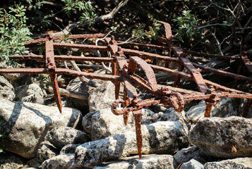 Alte verrostete Egge auf Steinmauer
