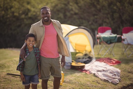 Father and son standing with arm around in park