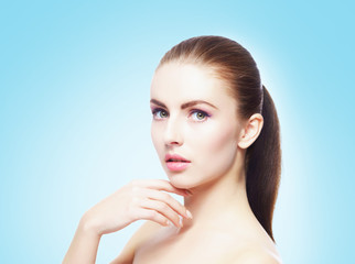 Portrait of young, beautiful and healthy woman: over cyan background. Healthcare, spa, makeup and face lifting concept.