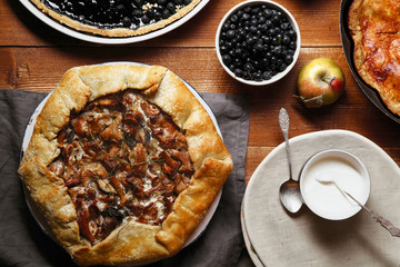 Traditional autumn pies arranged on red wooden rustic table. Chanterelle mushrooms, blueberry and sweet apple fillings. Top view.