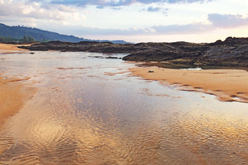 Nang Thong Beach at low tide in Khao Lak, Thailand. Seaside with sand dunes and reflection of blue sky with clouds in water. Natural background.