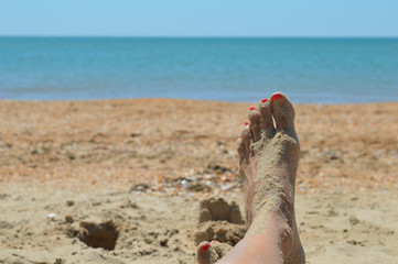 Девушка на пляже, ноги в песке.